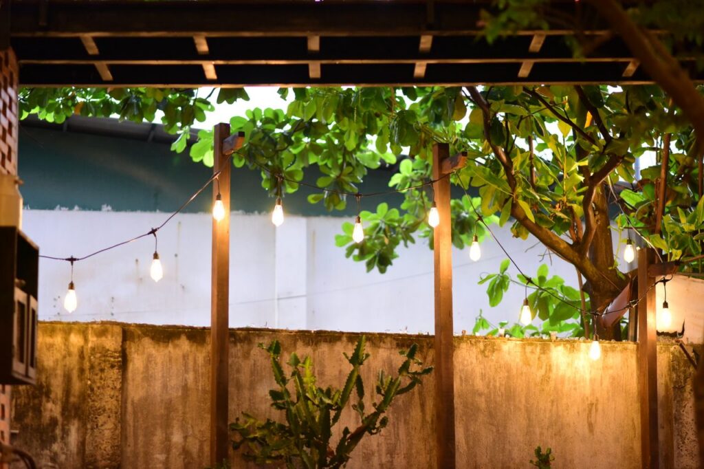 Warm string lights illuminate a backyard with lush foliage, creating a cozy outdoor ambiance.