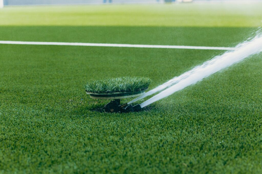 An active sprinkler watering a vibrant green sports field, enhancing the lush grass surface.