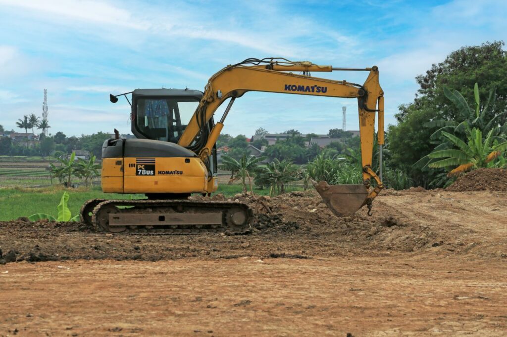 Yellow excavator on a rural construction site on a sunny day.